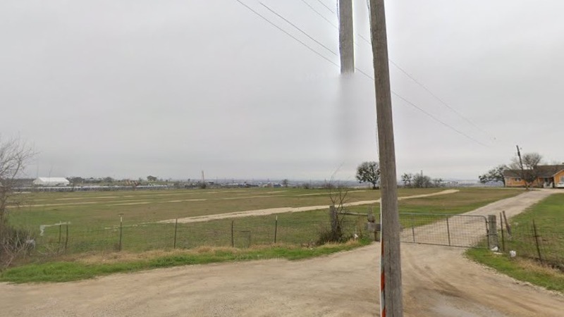 The gravel driveway into Lot Z from Elroy Road, with the gate and utility pole at the entrance